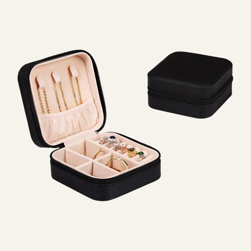 The black jewelry case open with ring rolls and necklace hooks, beside it closed