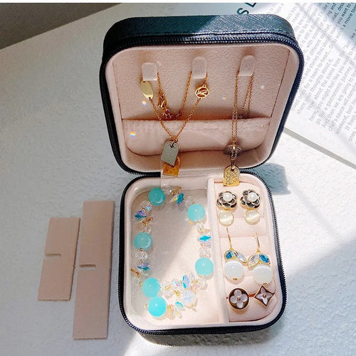 The case open on a table with rings, earrings and chains inside